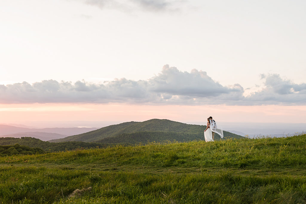 Wide shot of the bride and groom looking at the mountains and watching the sunset.