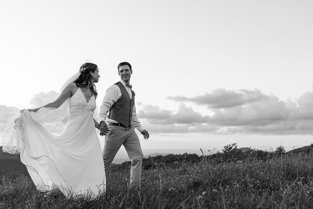 Black and white photo of the bride and groom walking together in the mountains at Max Patch.