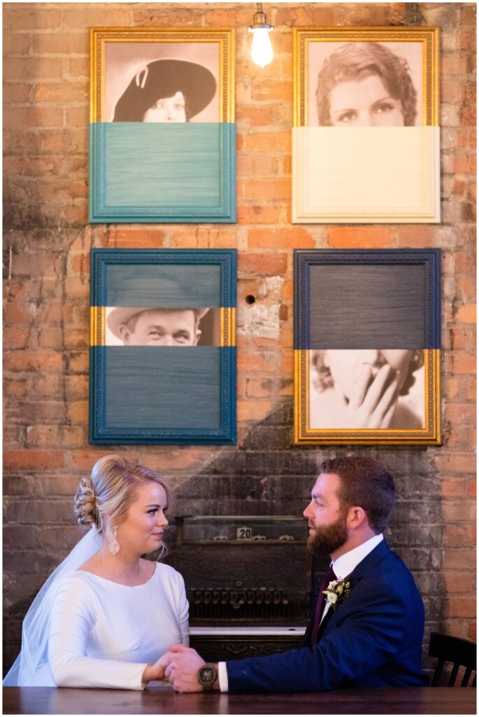 the bride and groom sitting at a table together holding hands