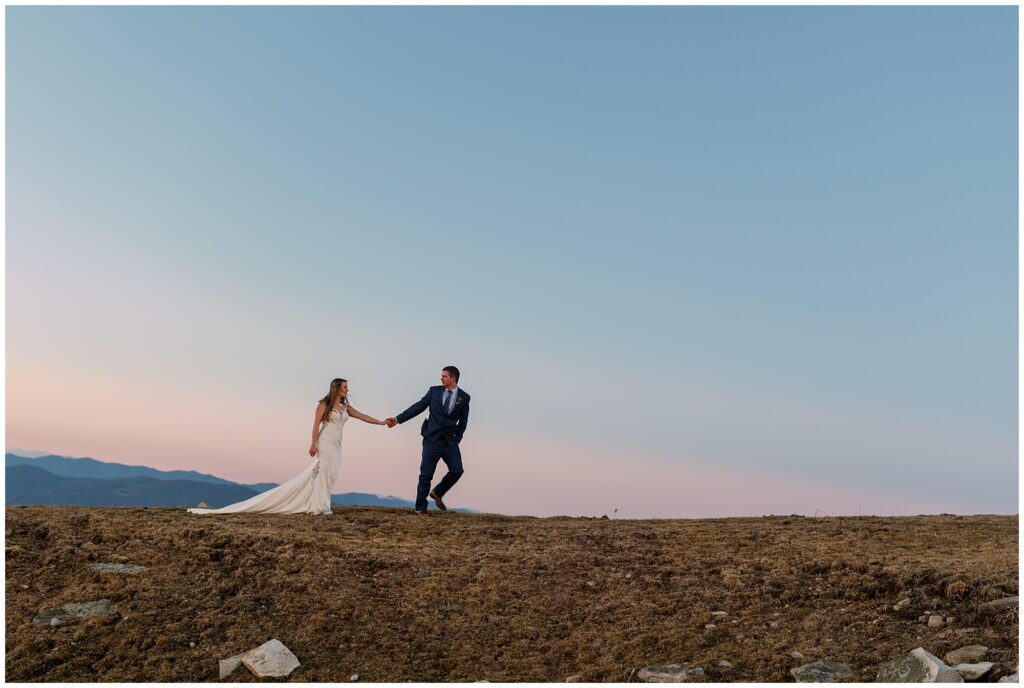 The groom leads his bride up the hill at Bearwallow mountain after their winter elopement ceremony.