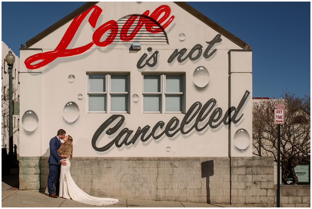 The bride and groom visited the famous love is not cancelled art mural at Spicer Green Jewelry in Asheville during their pandemic elopement.