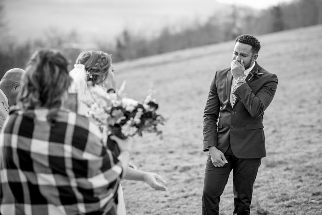 Black and white image of a groom seeing his bride for the first time.