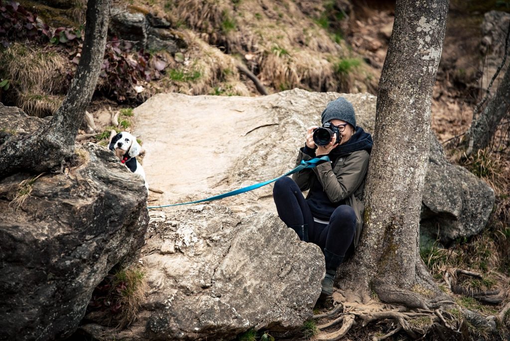 Legacy and legend photographer kneels behind a rock to get the shot during a family adventure session.